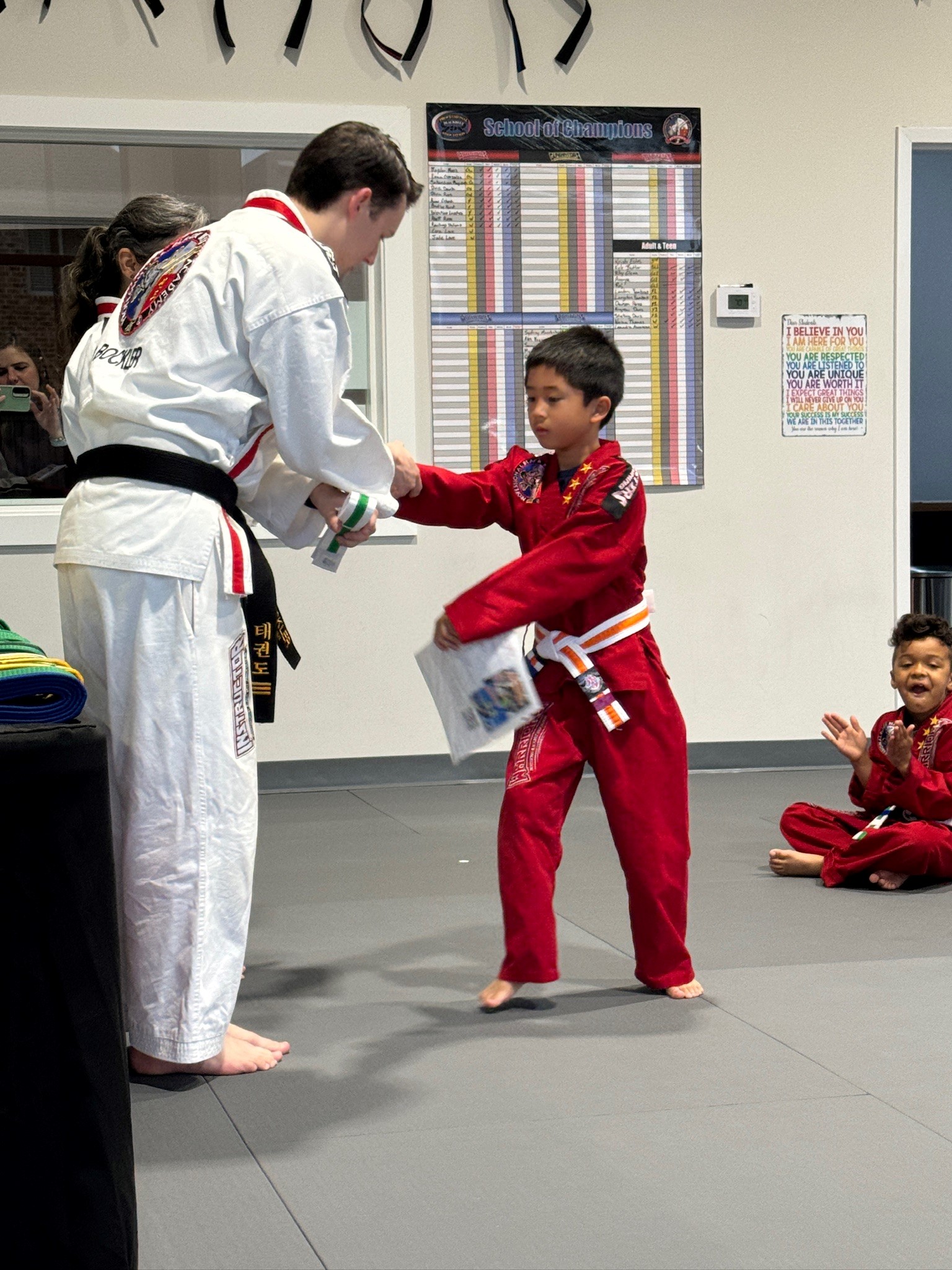 Sebastian receiving his new belt from Mr. Bockler